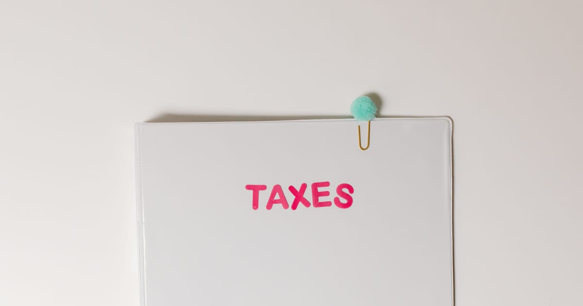 A white document folder labelled "TAXES" in pink marker