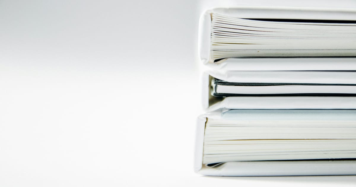 A neat stack of white document folders on a white surface