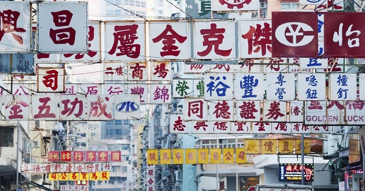 Dense traditional shop signs over a Hong Kong street, including a securities brokerage sign